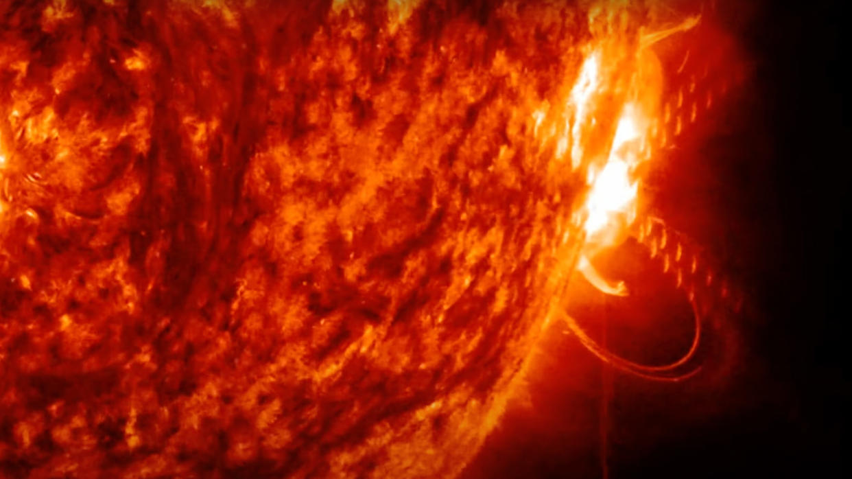  Closeup of the sun's orange surface, showing a bright-white flare erupting from a spot on the limb. 