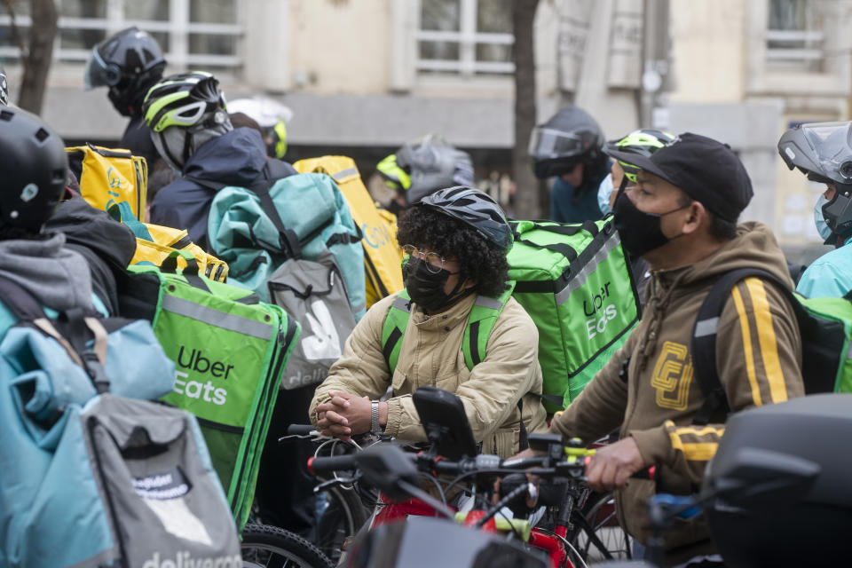 Delivery riders gather to protest outside the Spanish parliament in Madrid, Wednesday March 3, 2021. Food delivery workers have staged protests across Spain, urging the government to approve a promised law granting them the right to choose between being company staff or self-employed. Media reports said more than 2,000 delivery riders gathered to protest in at least 10 Spanish cities on Wednesday. (AP Photo/Paul White)