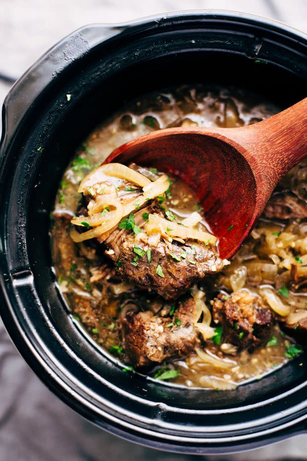 french onion pot roast in slow cooker with wooden spoon