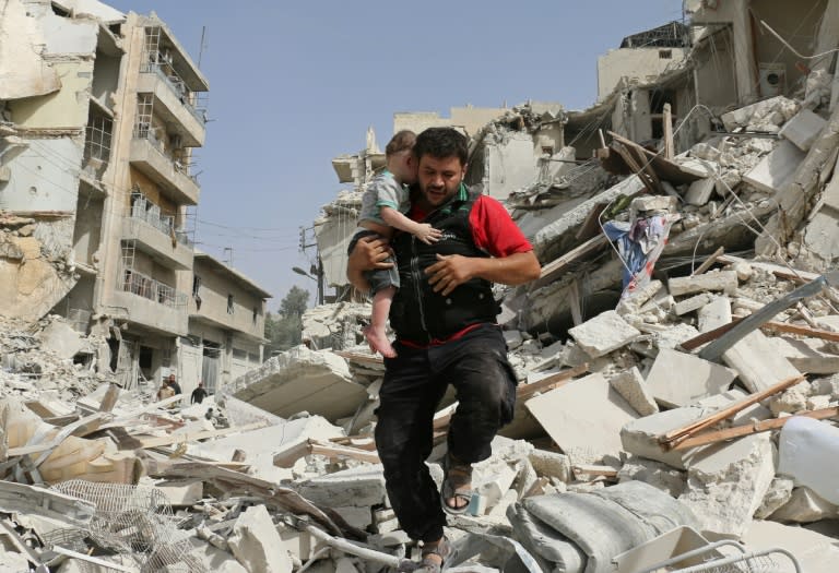 A Syrian man carries a baby after removing him from the rubble of a destroyed building following a reported air strike in the Qatarji neighbourhood of the northern city of Aleppo on September 21, 2016