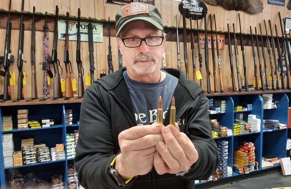 Larry Babal, salesman at Sporting Goods Discounters in Johnstown, holds a .308 rifle shell with a lead bullet beside a .243 caliber red-tipped copper bullet Feb. 23, 2022. Some hunters are considering copper bullets for hunting deer.