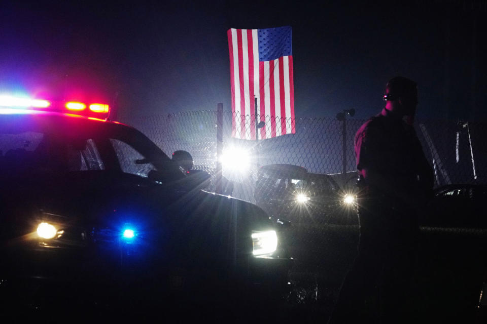 A police officer stands at his car early Sunday, July 14, 2024, closing access to the site of the rally  (Sue Ogrocki / AP)