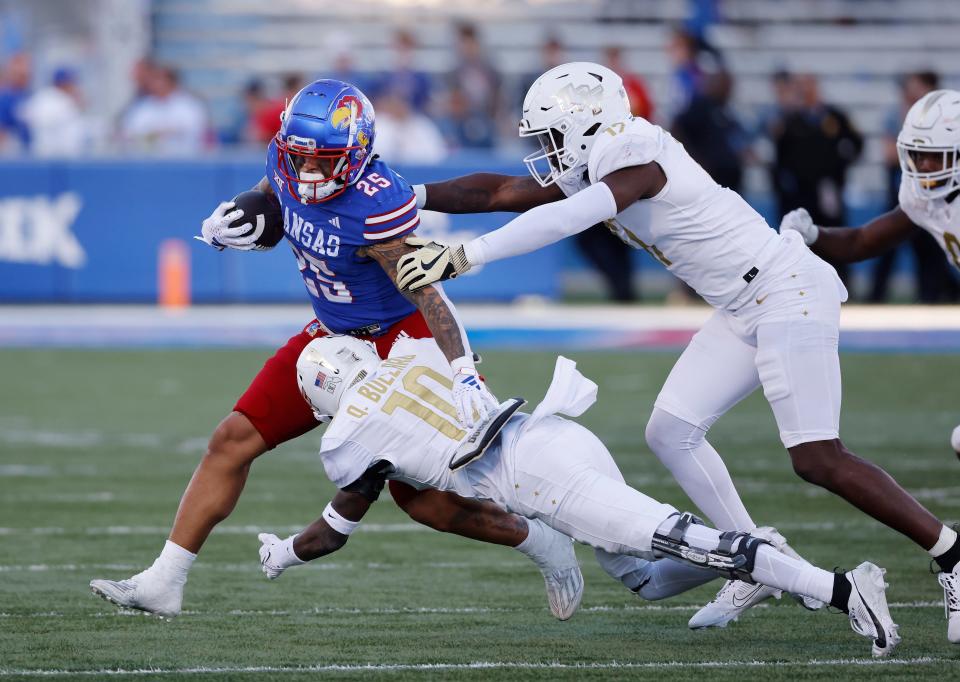 Kansas running back Dylan McDuffie (25) is chased by Central Florida linebacker Rian Davis (17) and defensive back Quadric Bullard (10) during the second half of an NCAA college football game Saturday, Oct. 7, 2023, in Lawrence, Kan. (AP Photo/Colin E. Braley)
