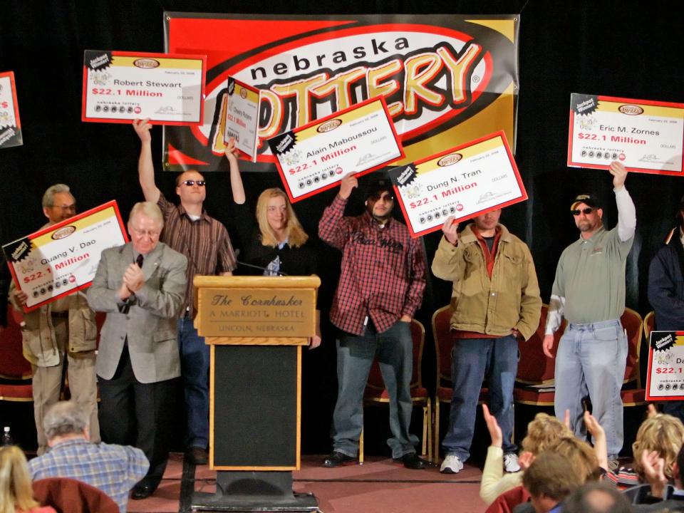 In this Feb. 22, 2006 file photo, the eight ConAgra plant workers hold up their ceremonial checks after winning the $365 million dollar Nebraska Powerball lottery at a news conference in Lincoln, Nebraska