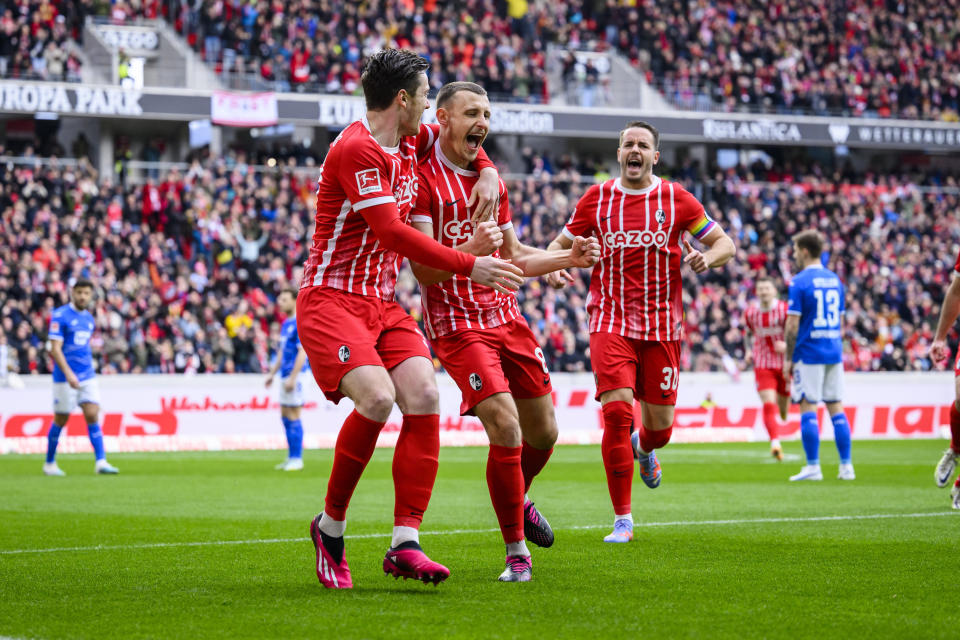 Freiburg's Maximilian Eggestein, center, celebrates with Freiburg's Michael Gregoritsch, left, and Freiburg's Christian Gunter, right, after his goal for 1:0 during the German Bundesliga soccer match between TSG 1899 Hoffenheim and SC Freiburg in Freiburg im Breisgau, Germany, Sunday March 12, 2023. (Tom Weller/dpa via AP)