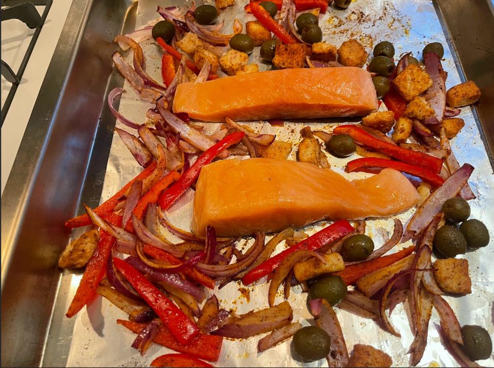 Salmon and baked veggies on a foil-lined pan.