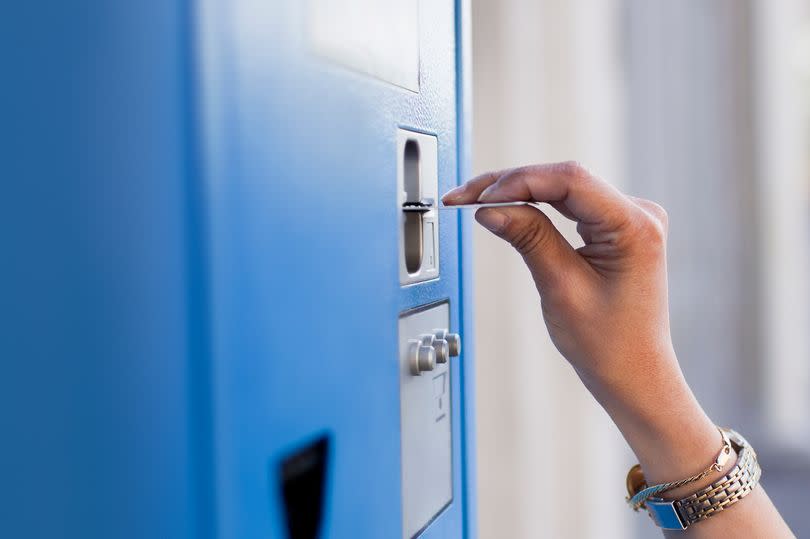 Person buying parking ticket with credit card at ticket machine.