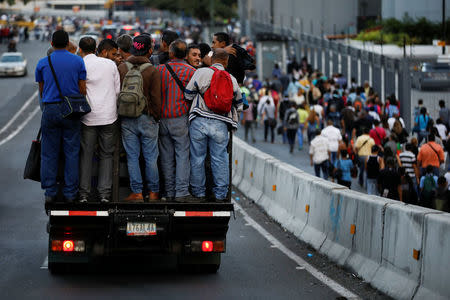 People ride in a truck and walk on a street during a blackout in Caracas, Venezuela February 6, 2018. REUTERS/Carlos Garcia Rawlins