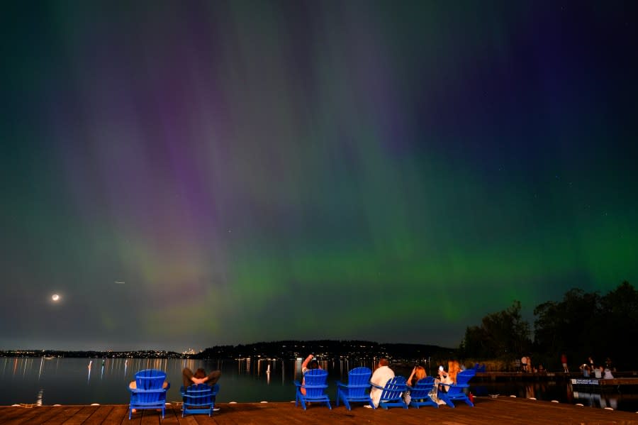 People take photos of the Northern Lights, or Aurora Borealis, as they glow over Lake Washington, in Renton, Wash., on Friday evening, May 10, 2024. (AP Photo/Lindsey Wasson)