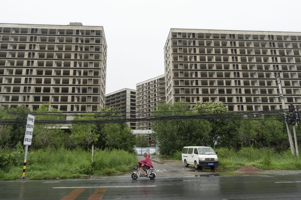 A rider passes by an abandoned construction project on the outskirts of Beijing, Thursday, July 25, 2024. (AP Photo/Ng Han Guan)