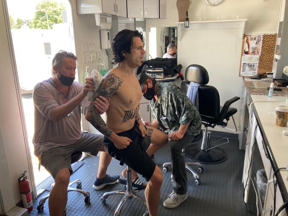 Dave Snyder puts makeup on actor Sebastian Stan as Tommy Lee for the Hulu show "Pam and Tommy." Snyder had to put around 50 separate fake tattoos on Stan for each day of filming.