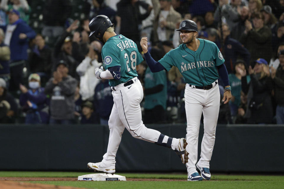 Seattle Mariners' Eugenio Suarez (28) celebrates with first base coach Kristopher Negron after hitting a two-run home run against the Tampa Bay Rays during the first inning of a baseball game Friday, May 6, 2022, in Seattle. (AP Photo/Jason Redmond)