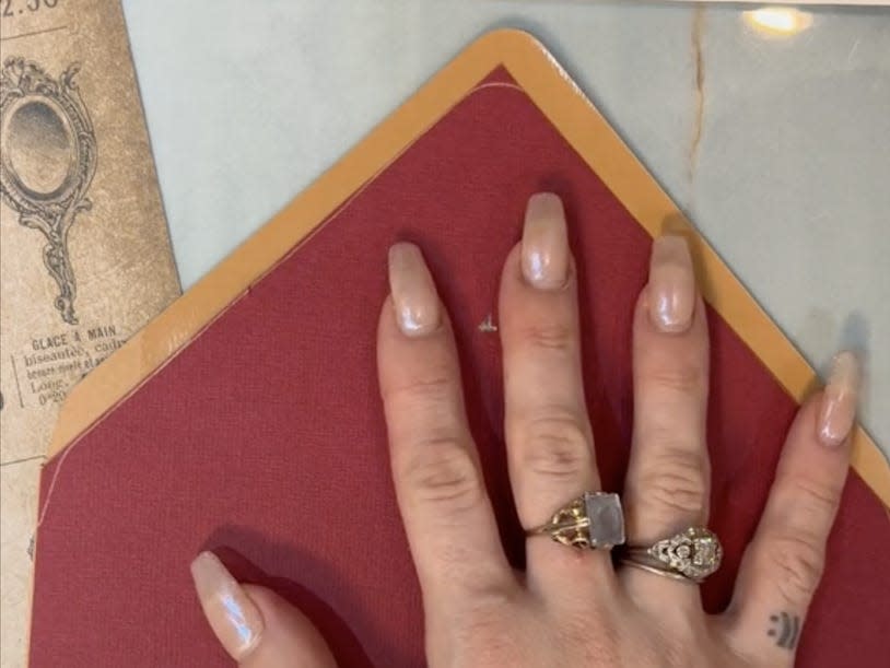 a screenshot of hands hlding a red stencil of an envelope over a brown envelope