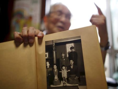 Atsushi Hoshino, a 87-year-old Hiroshima atomic bombing survivor, former college professor and ex-president of Fukushima University, shows a family photo taken in 1941 (he is standing in the centre) at his home in Fukushima, Japan, July 30, 2015. REUTERS/Toru Hanai