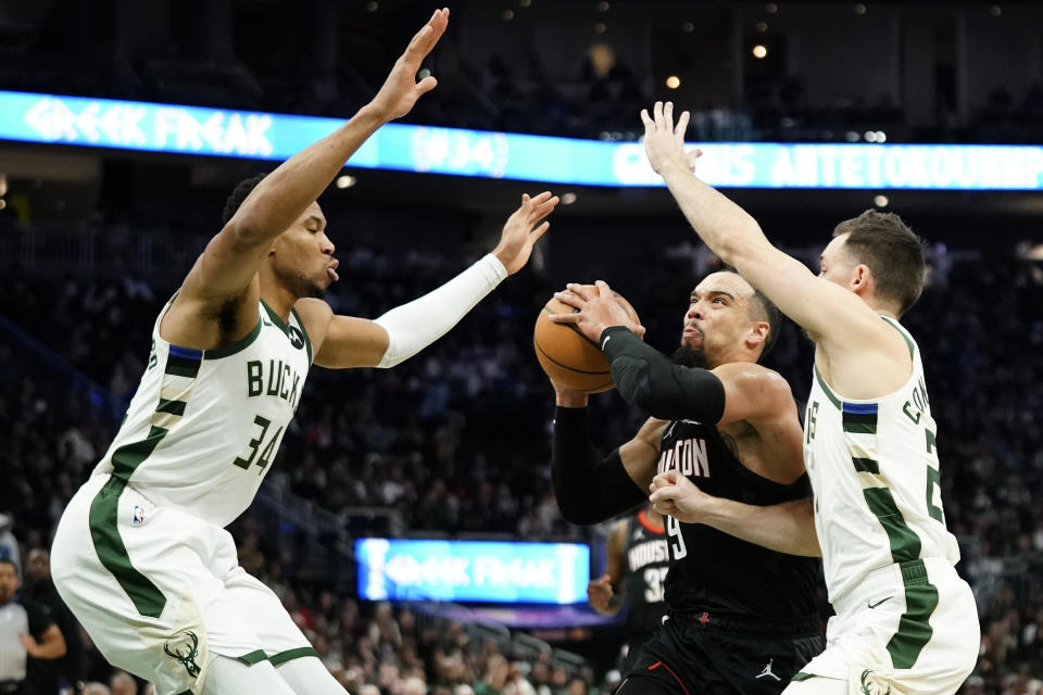 Houston Rockets' Dillon Brooks (9) drives to the basket between Milwaukee Bucks' Giannis Antetokounmpo (34) and Pat Connaughton during the first half of an NBA basketball game Sunday, Dec. 17, 2023, in Milwaukee. (AP Photo/Aaron Gash)