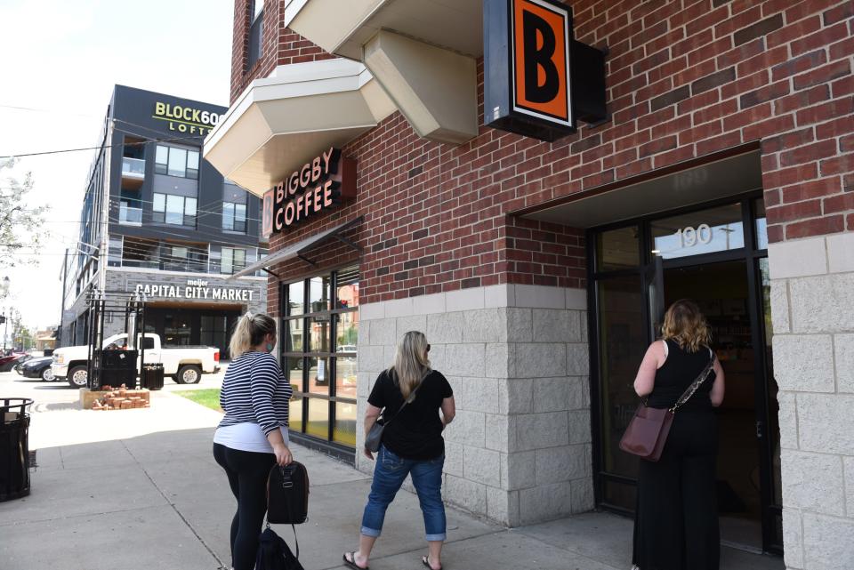 People arrive at Biggby Coffee Thursday, May 12, 2022, to find the lobby closed. Signage on the doors indicates only drive-thru service is available.