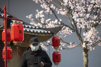 A man wearing a mask looks out from a decoration promoting a movie in Beijing, China on Wednesday, Feb. 19, 2020. Even as authorities went door to door to find the infected in Wuhan, the epic center of the viral outbreak, Beijing was showing signs of coming back to life this week, with road traffic at around a quarter of usual, up from virtually nothing a week ago. While most restaurants, stores and office buildings remained closed, others had reopened. (AP Photo/Ng Han Guan)