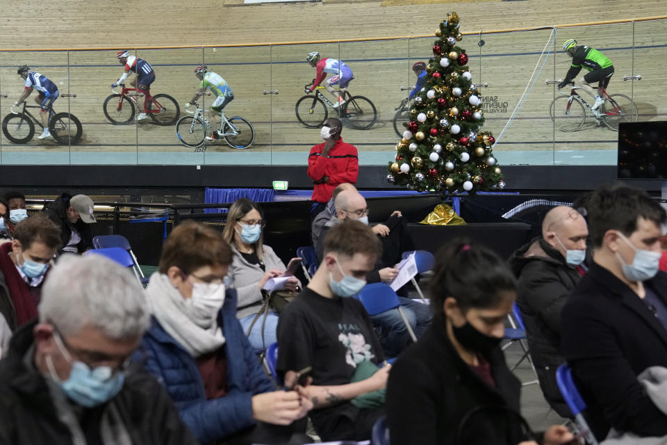 People wait after beeing vaccinated as riders train at the National Velodrome in Saint-Quentin-en-Yvelines, west of Paris, France, Friday, Dec. 17, 2021. The government is holding a special virus security meeting Friday to address growing pressure on hospitals in France from rising infections. (AP Photo/Christophe Ena)