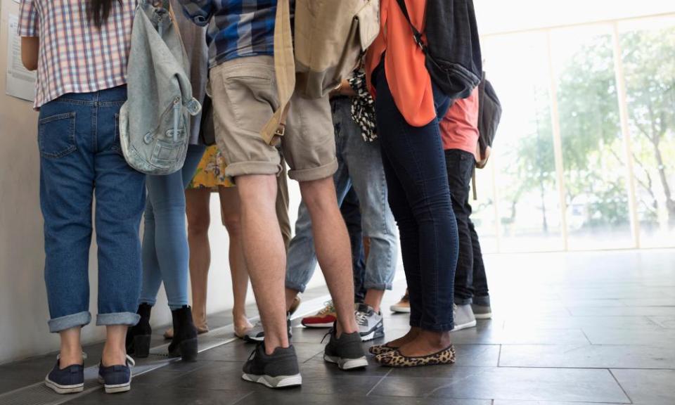 Low-angle view of university students standing in corridor and looking at test results