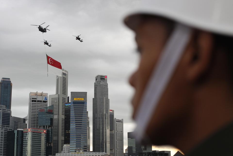 Helicopters fly past with a Singapore flag during Singapore's 49th National Day Parade at the floating platform in Marina Bay August 9, 2014. REUTERS/Edgar Su (SINGAPORE - Tags: SOCIETY ANNIVERSARY MILITARY)