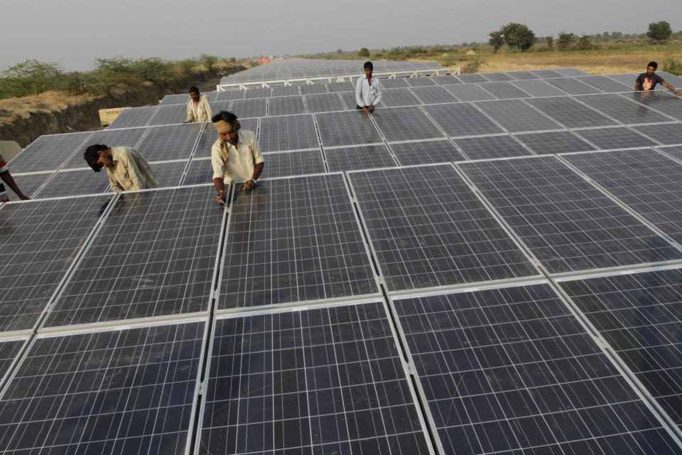 FILE - Indian laborers work amid installed solar panels atop the Narmada canal at Chandrasan village, outside Ahmadabad, India, Feb. 16, 2012. The project brings water to hundreds of thousands of villages in the dry, arid regions of western India’s Gujarat state. (AP Photo/Ajit Solanki, File)