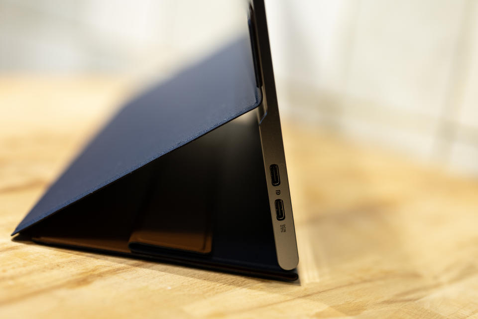 A black and silver ASUS ZenScreen MQ16AH portable monitor on a wooden brown desk