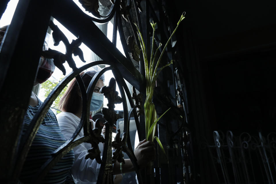 A devotee wearing a face mask to prevent the spread of the coronavirus holds palm fronds as she attends a Palm Sunday mass outside the Saint Peter Parish Church in Quezon city, Philippines, Sunday, March 28, 2021. The government banned religious activities during the Holy Week as it enters into stricter lockdown measures starting next week while the country struggles to control an alarming surge in COVID-19 cases. (AP Photo/Aaron Favila)