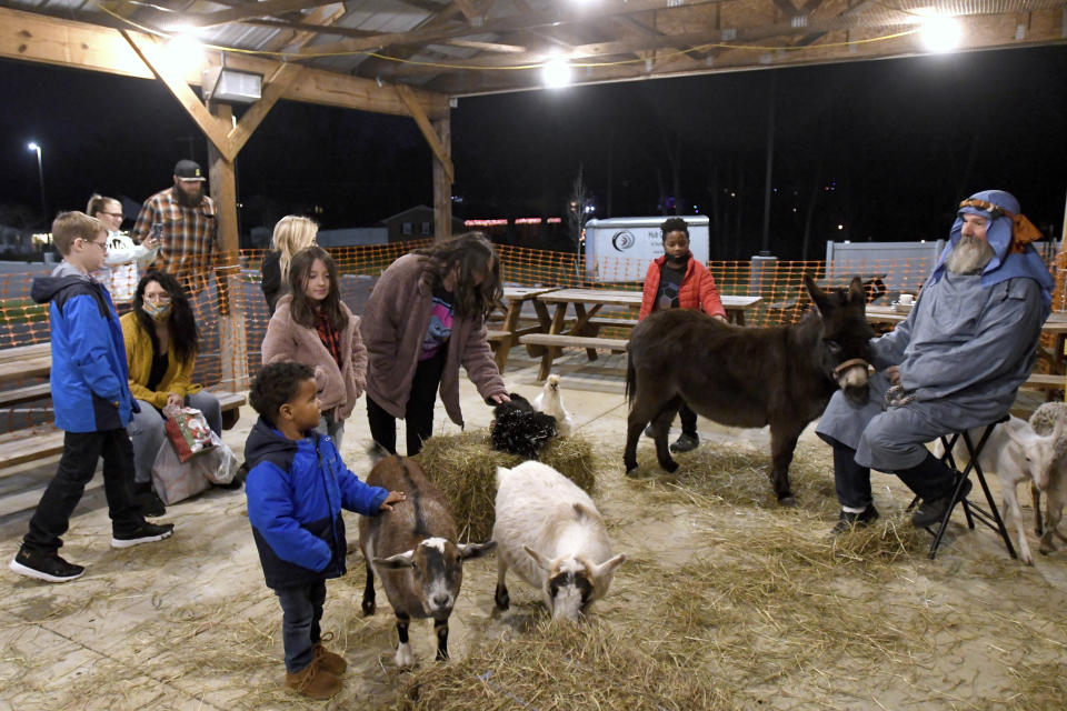 Children explore a petting zoo, supervised by Gary Shank, right, of Hagerstown, Md., during Prison Fellowship's Angel Tree event for children of the incarcerated, Sunday Dec. 19, 2021 at Hub City Vineyard church in Hagerstown. The Prison Fellowship's Angel Tree is expected to deliver gifts to about 300,000 kids nationwide this year. (AP Photo/Steve Ruark)