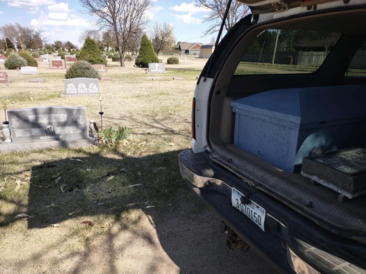 A casket with the body of Eric Cummings along with a headstone in the back of Barry Cummings' Chevy Suburban, parked at a cemetery.