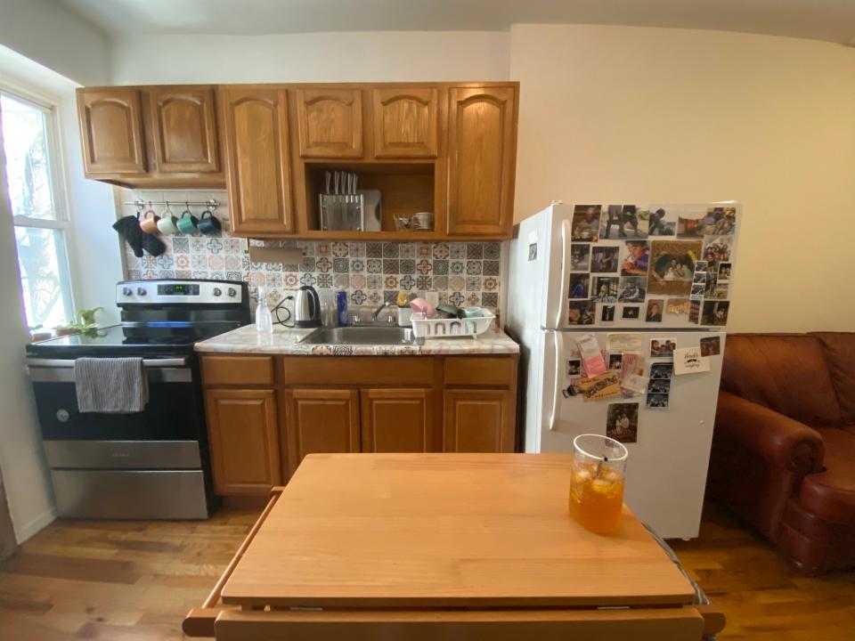 The author's kitchen is seen with a cart in the forefront and a counter, sink, fridge, and oven behind it