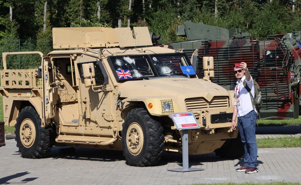 A visitor takes a selfie photo in front of an Armored Vehicle Husky (International MXT-MV by Navistar, Inc), captured in Ukraine in 2023, during a propaganda exhibition of captured Ukrainian weapons, on August 15, 2023.