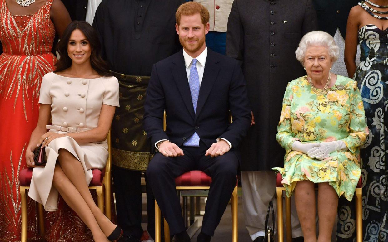 Meghan, Duchess of Sussex, Prince Harry and Queen Elizabeth II pose for a picture during the Queen's Young Leaders Awards Ceremony at Buckingham Palace in London - JOHN STILLWELL/AFP