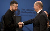 Ukrainian President Volodymyr Zelenskyy, left, and German Chancellor Olaf Scholz, right, shake hands during the award ceremony of the Charlemagne Prize in Aachen, Germany, Sunday, May 14, 2023. Zelenskyy is in Aachen to receive the International Charlemagne Prize, awarded to him and the people of Ukraine. (Ina Fassbender/Pool Photo via AP)