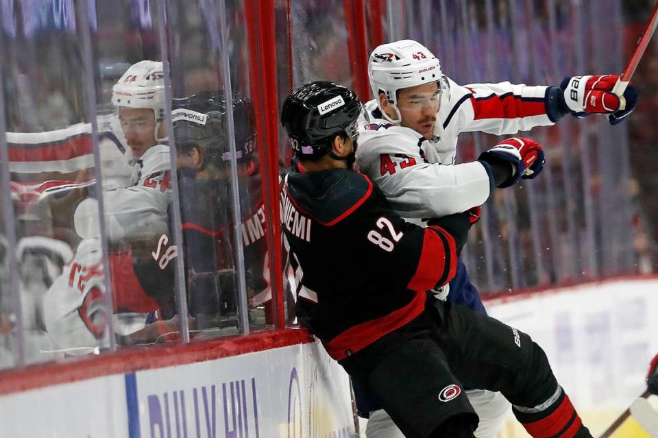 Washington Capitals’ Tom Wilson (43) checks Carolina Hurricanes’ Jesperi Kotkaniemi (82) into the boards during the first period of an NHL hockey game in Raleigh, N.C., Sunday, Nov. 28, 2021. (AP Photo/Karl B DeBlaker)