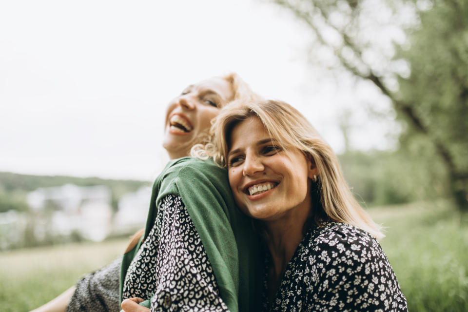 Two women smiling and hugging outdoors, expressing joy