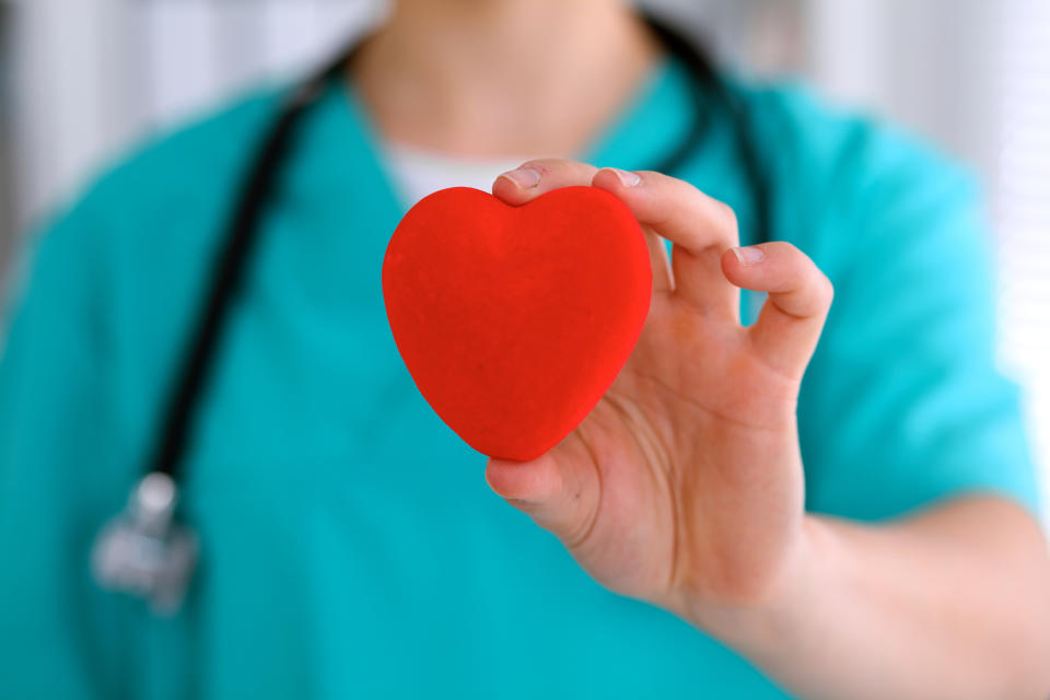 Female surgeon doctor with stethoscope holding heart