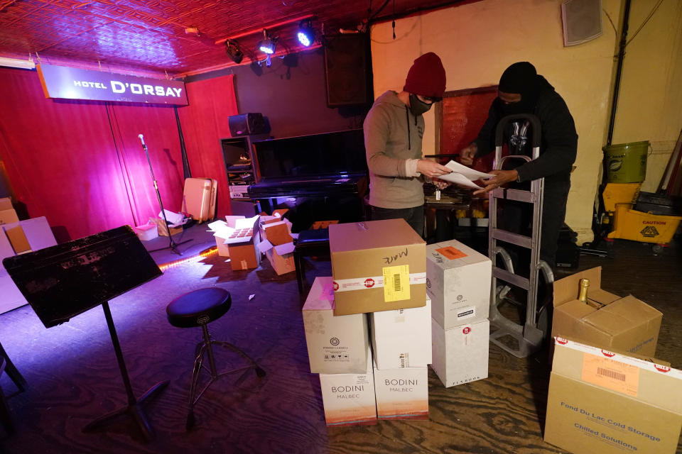 Bartender Alex Wright, left, reviews paperwork on a wine delivery at Barbès, a popular music venue and bar that has been converted to a bottle shop to survive the winter during the coronavirus pandemic, Tuesday, Dec. 1, 2020, in New York. (AP Photo/Kathy Willens)