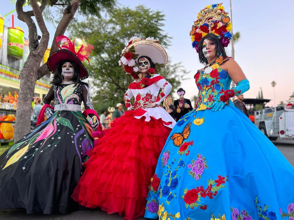 Three women show off their elaborate Day of the Dead makeup and dresses during the Día de Los Muertos celebration at the Hollywood Forever Cemetery in Los Angeles on Saturday, Oct. 28, 2023.