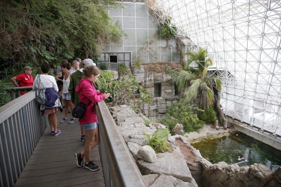 In this July 31, 2015 photo, tourists check out the Biosphere 2 Ocean, holding a million gallons of seawater, designed as an enclosed ecological system to research interactions within ecosystems, in Oracle, Ariz. University of Arizona officials say that 25 years after that New Age-style experiment in the Arizona desert, the glass-covered greenhouse thrives as a singular site for researchers from around the world studying everything from the effects of the ocean’s acidification on coral to ways of ensuring food security. (AP Photo/Ross D. Franklin)