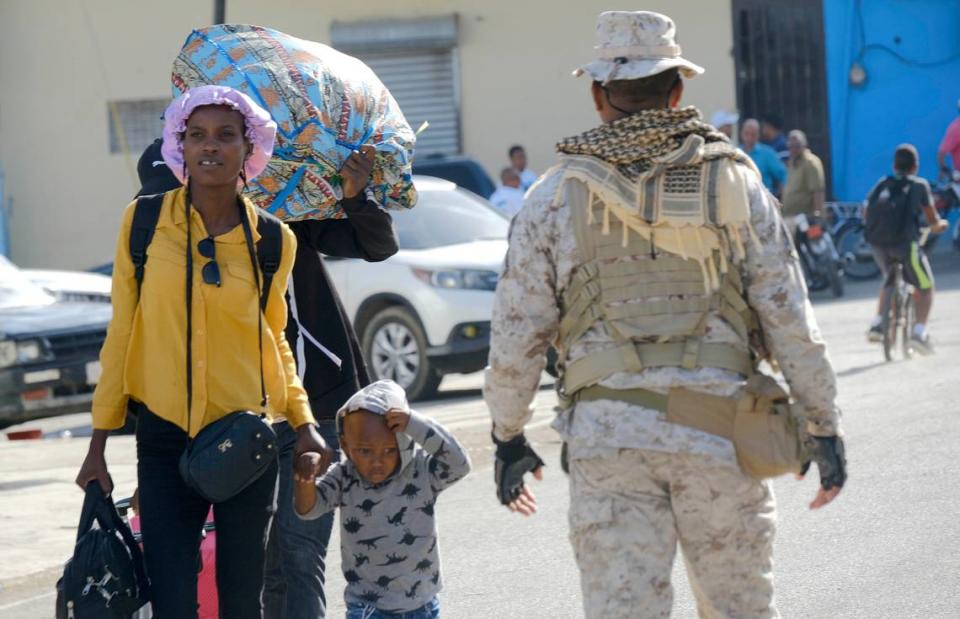 A mother and child walk next to a Dominican Republic security officer on a border bridge between Dajabón, Dominican Republic, and Haiti, Thursday, Sept. 14, 2023. The president of the Dominican Republic announced Thursday that he would close all borders with neighboring Haiti starting Friday in response to the construction of a supposed canal on Haitian soil that targets waters from the Massacre River, which runs along the border shared by both countries.