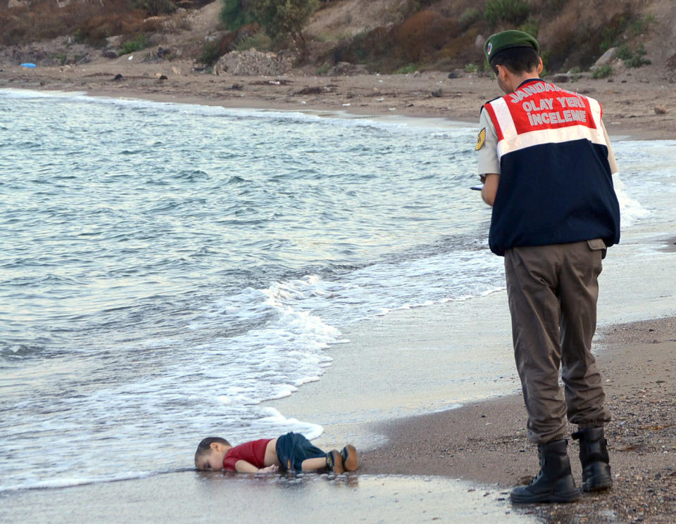 A Turkish paramilitary police officer observes the lifeless body of 3-year-old Aylan Kurdi on a Turkish beach