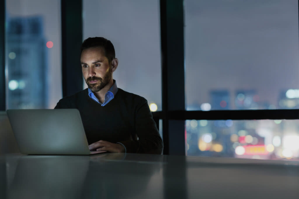 Man viewing laptop computer in office at night