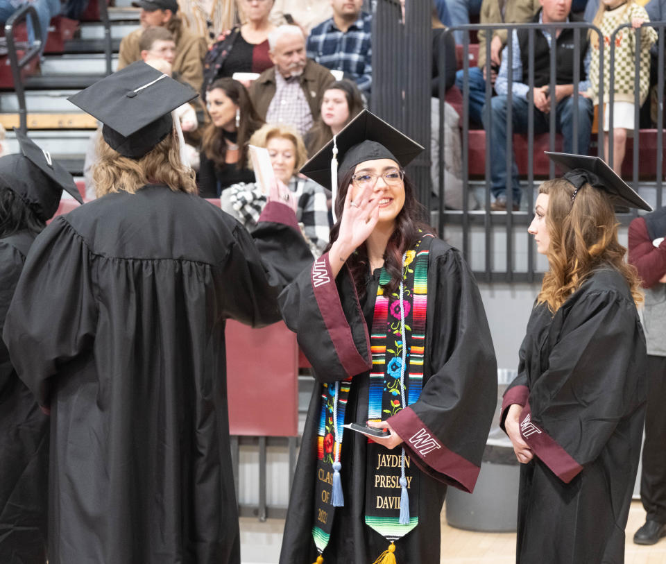 A graduate waves at a family member at the WT commencement ceremony Saturday morning at the First United Bank Center in Canyon.