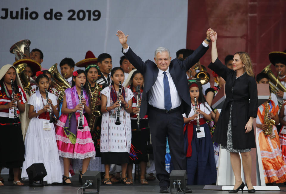 Mexico's President Andres Manuel Lopez Obrador and his wife Beatriz Gutiérrez Müller greet the crowd at a rally to celebrate the one-year anniversary of his election, in Mexico City's main square, the Zocalo, Monday, July 1, 2019.(AP Photo/Fernando Llano)