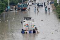 Men push a truck through a flooded road during the monsoon rain, as the outbreak of the coronavirus disease (COVID-19) continues, in Karachi