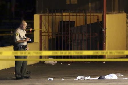 A Los Angeles County Sheriff's deputy inspects the scene where a pedestrian was killed in a hit-and-run crash reportedly involving rap mogul Marion "Suge" Knight, in Compton, California January 29, 2015. REUTERS/Jonathan Alcorn