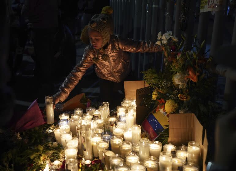 A Venezuelan migrant girl lights a candle during a vigil for the victims of a fire at an immigration detention center that killed dozens, in Ciudad Juarez, Mexico, Tuesday, March 28, 2023. According to Mexican President Andres Manuel Lopez Obrador, migrants fearing deportation set mattresses ablaze at the center, starting the fire. (AP Photo/Fernando Llano)