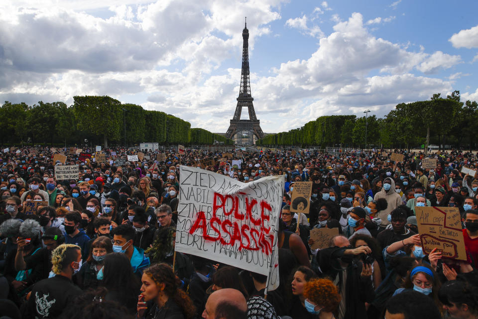 FILE - In this June 6, 2020 file photo, hundreds of demonstrators gather near the Eiffel Tower, some with a banner reading "Police, murderers" during a demonstration in Paris, France, to protest against the recent killing of George Floyd, a Black man who died in police custody in Minneapolis, U.S.A. As videos helped reveal many cases of police brutality, French civil rights activists voiced fears that a new security law would threaten efforts by people from minorities and poor neighborhoods to document incidents involving law enforcement officers. French President Emmanuel Macron's government is pushing a new security bill that would notably make it illegal to publish images of officers with intent to cause them harm. (AP Photo/Francois Mori, File)