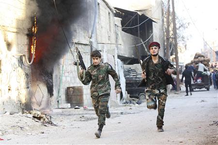 Shi'ite fighters, fighting along forces loyal to Syria's President Bashar al-Assad, run with their weapons along a deserted street in Hujaira town, south of Damascus November 21, 2013. REUTERS/ Alaa Al-Marjani