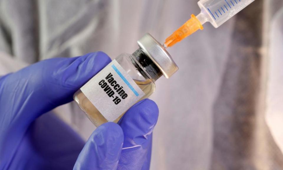 A woman holds a small bottle labeled with a “Vaccine COVID-19” sticker.